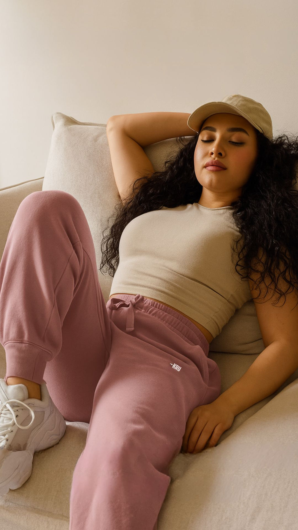 Woman in casual outfit sitting on a couch with a neutral background