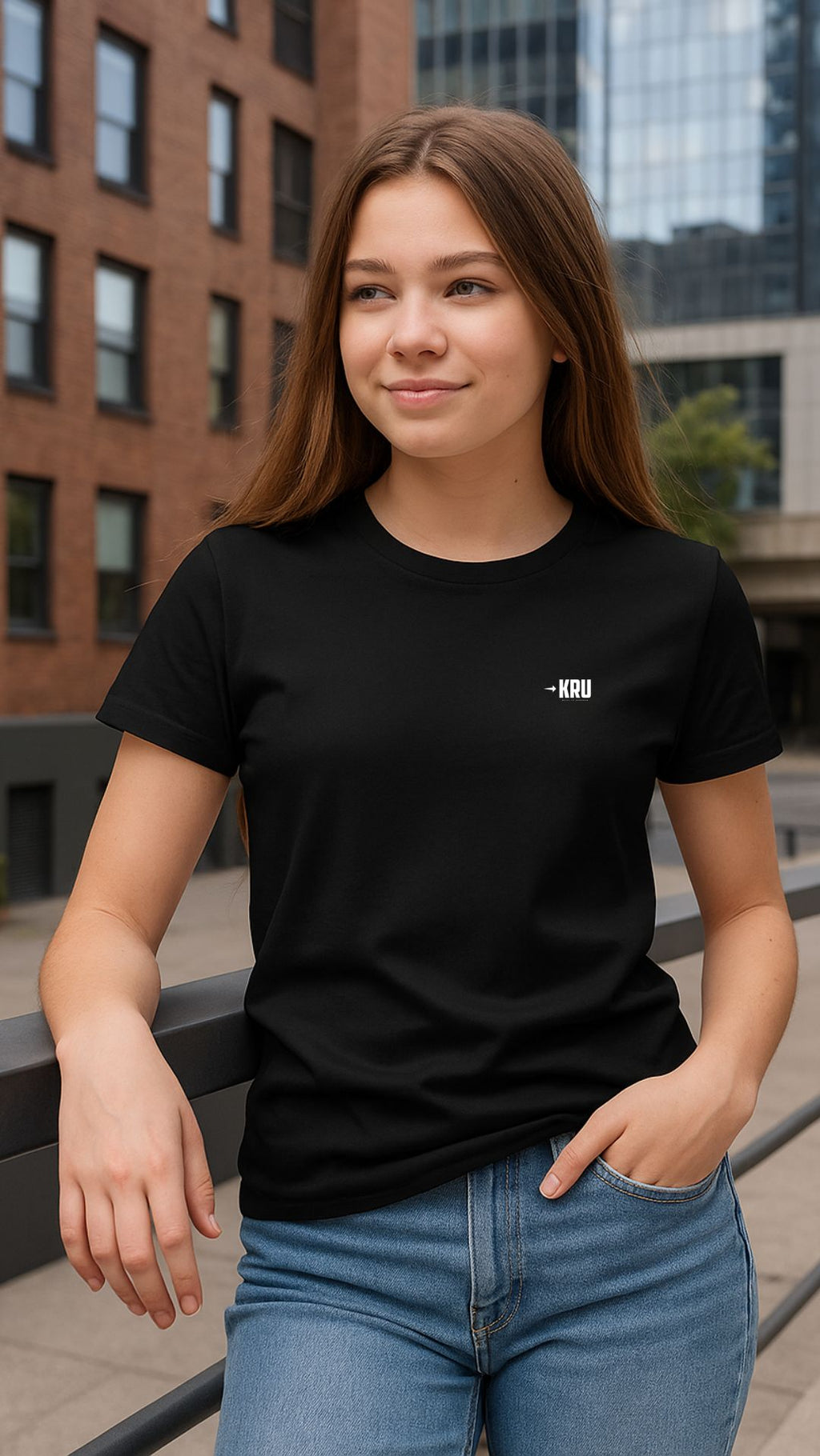 Woman wearing a black t-shirt with a small logo, standing outdoors.