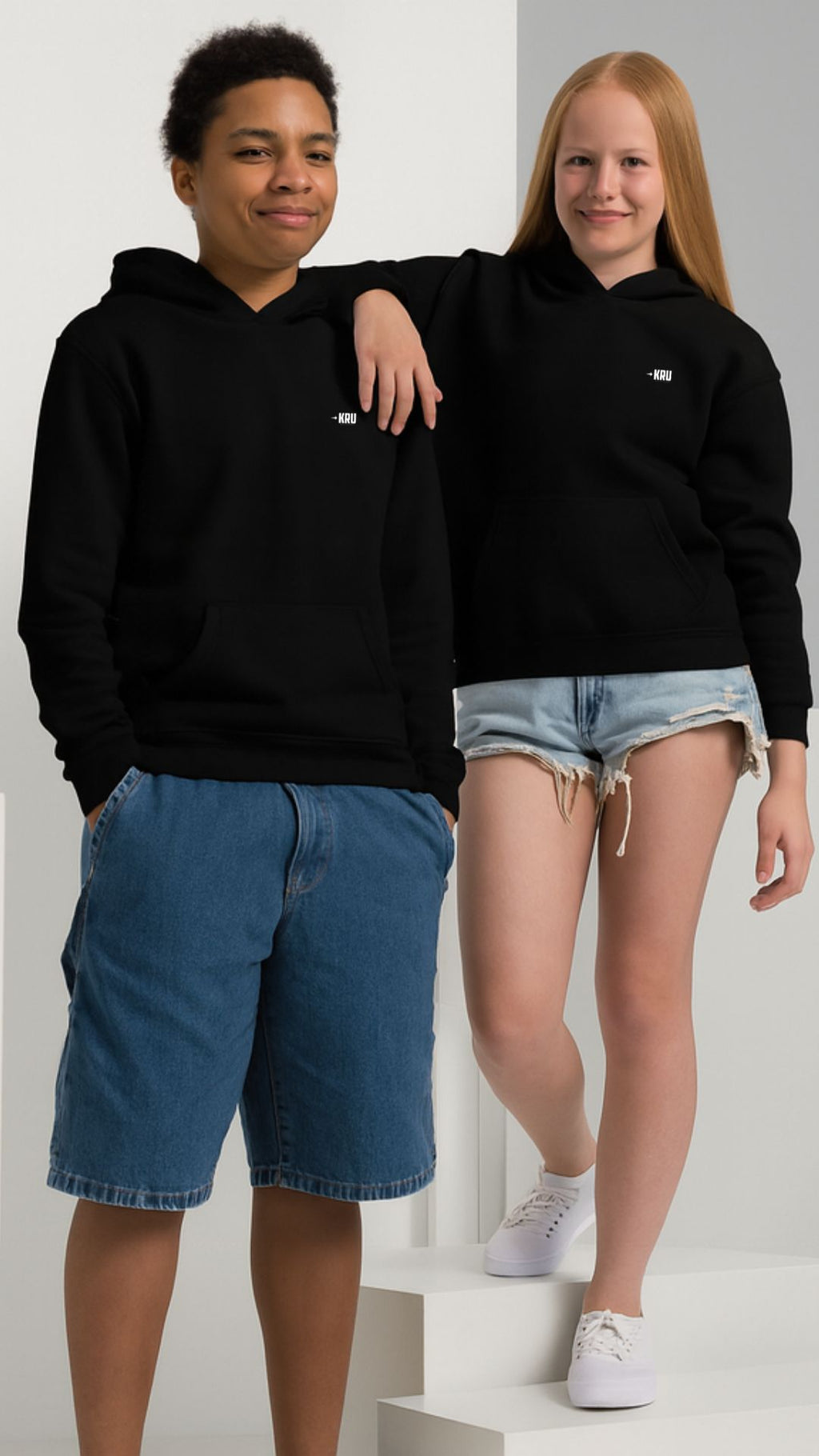 Two people wearing black hoodies and shorts on a white background