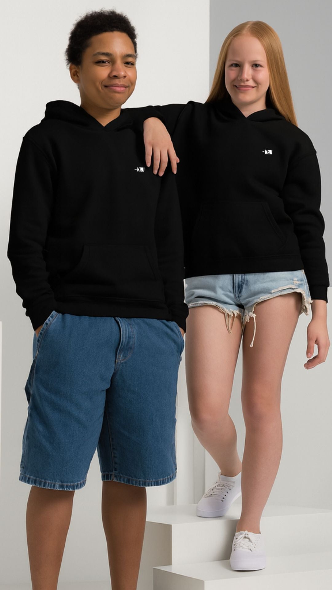 Two people wearing black hoodies and shorts on a white background
