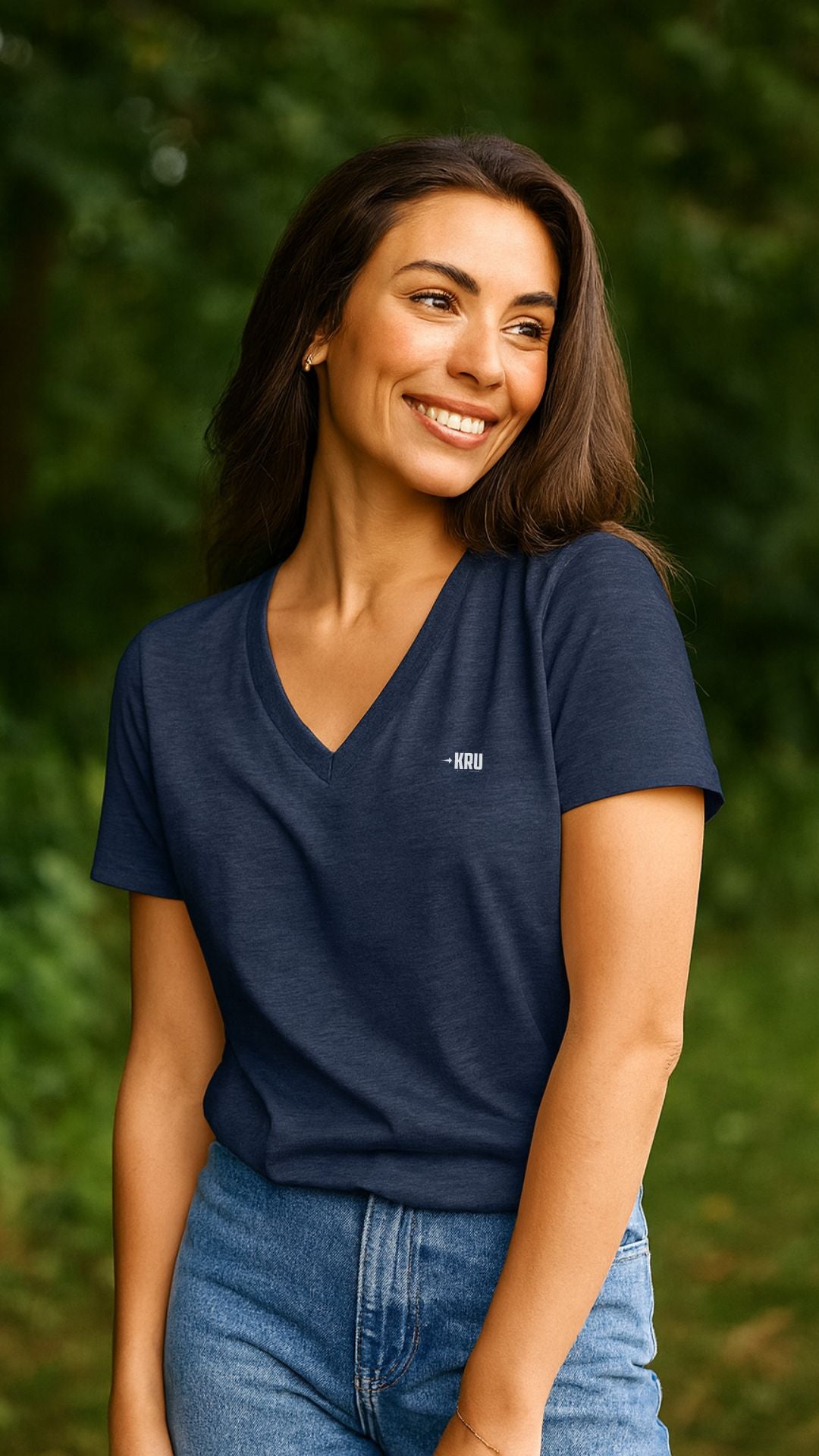 Woman wearing a navy blue t-shirt with a logo against a green outdoor background